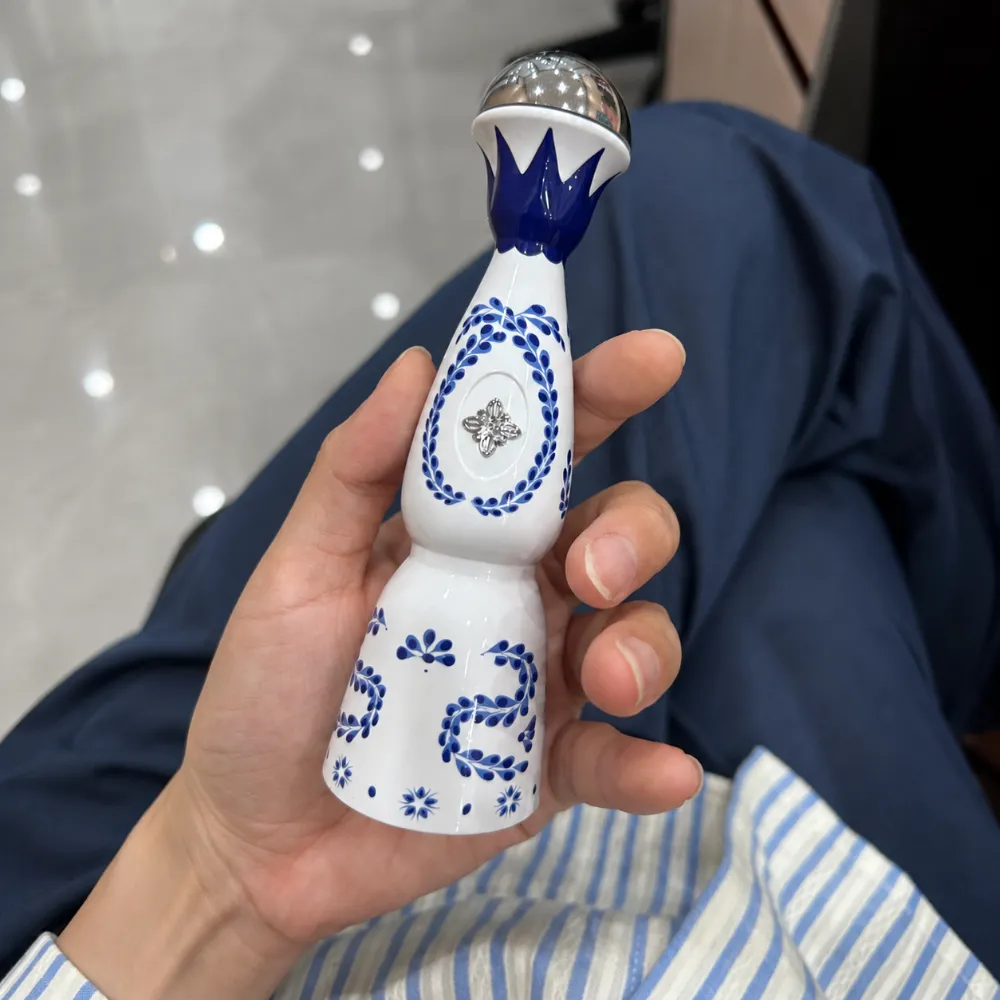 HUMO AZUL 24K Blue Edition: vaporizador azul y blanco con forma de botella, sostenido en la mano